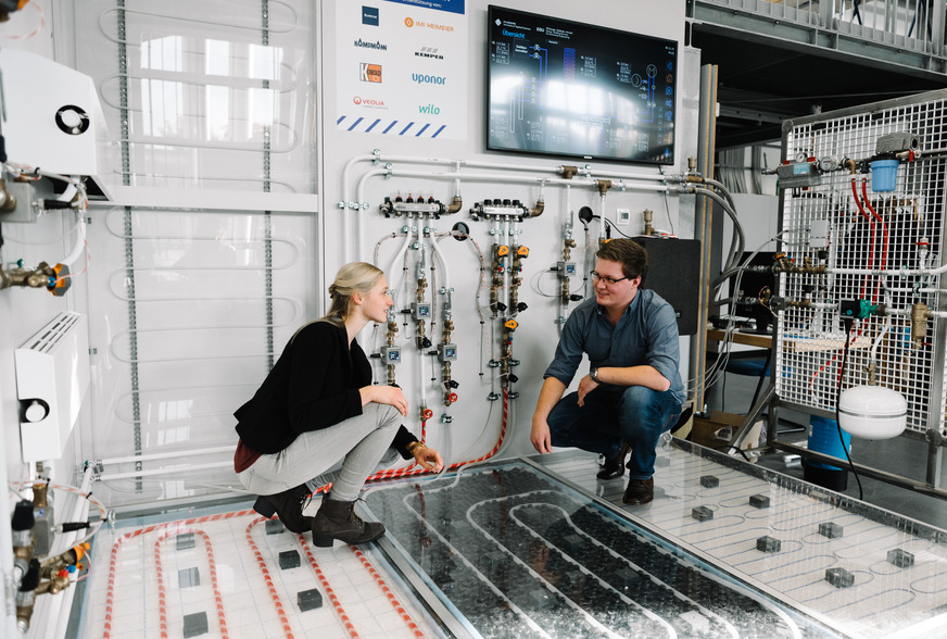 Allein drei verschiedene Arten von Fußbodenheizungen sind in dem Modellraum verbaut. Studentin Julia Heetpaß erklärt Kommilitone Gregor Plascher Unterschiede.