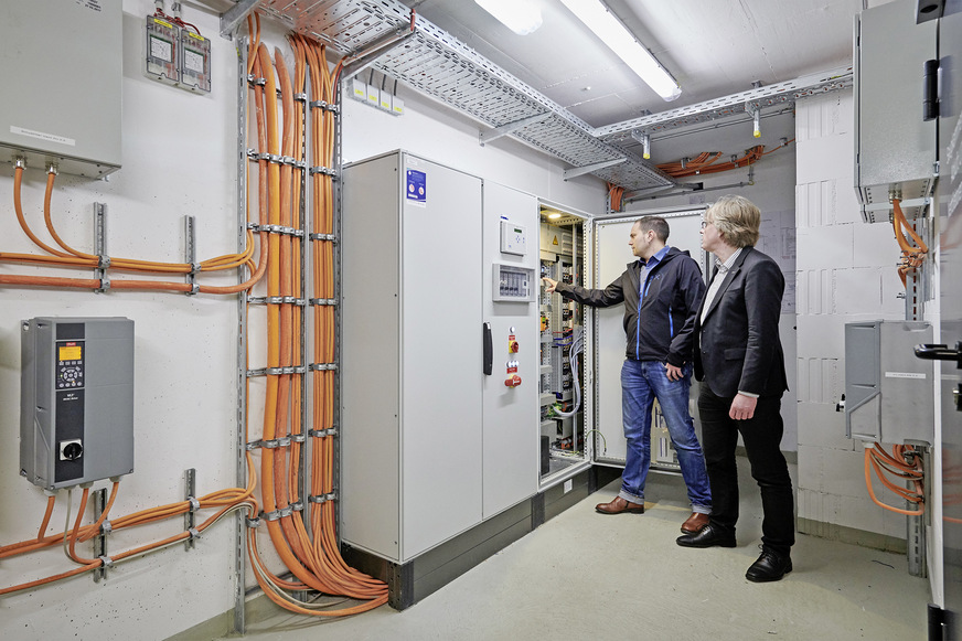 Bild 5: Die gesamte Lüftungs- und Rauchschutztechnik hat Systemair als Komplett­paket für die Tiefgarage des DomRömer konzipiert und inklusive vorverdrahteten Schaltschränken und Frequenzumrichtern montagefertig angeliefert. Die über­wiegend analoge Schalttechnik gehörte dabei zum Konzept, so Systemair-Manager Reiner Kelch (rechts), hier im Gespräch mit Projektingenieur Christof Stegmann.