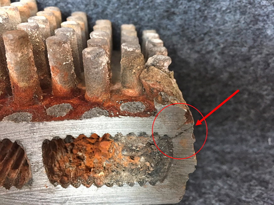 Bild 2: Defekter Wärmeerzeuger aus einer Aluminiumlegierung. Durch eingespülte Korrosionsprodukte und Kalkstein kam es zu einer lokalen Überhitzung, die zu einem Riß geführt hat.