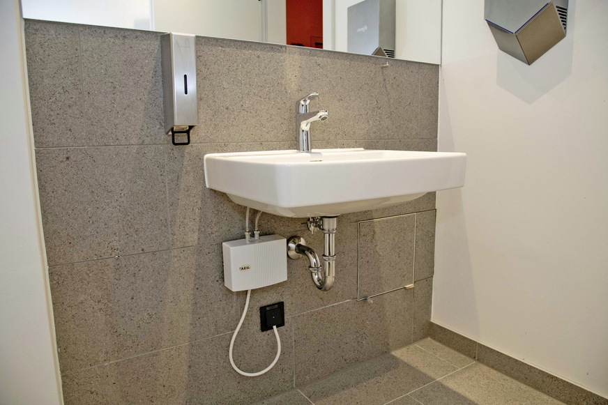 Bild 11:&nbsp;Auch im Gebäude haben Investoren und ­Planer auf Produkte von AEG Haustechnik gesetzt: In den WC-Anlagen wurden 40 elektronische Klein-Durchlauferhitzer MTE 440 als Untertisch­geräte installiert. Für warmes Wasser in den Duschbereichen sorgen zwei elektronische Durchlauferhitzer DDLE Easy. In den Teeküchen, Behandlungsräumen von Arztpraxen und weiteren Nutzungsbereichen übernehmen dies insgesamt 35 Untertisch- und Übertisch-Kleinspeicher.