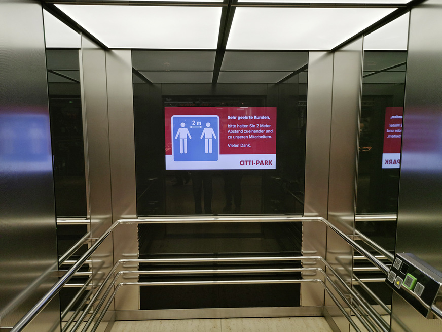 Bild 6: Bildschirm im Aufzug macht auf den empfohlenen Abstand aufmerksam.