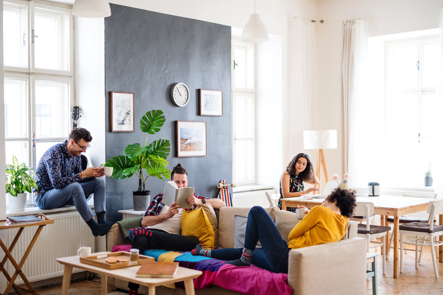 A group of young cheerful friends relaxing indoors, house sharing concept.