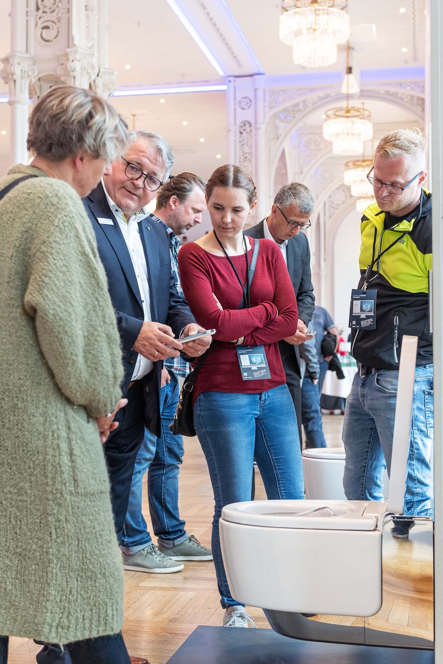 Besucher des Geberit BauTreffs nehmen das Dusch-WC Geberit AquaClean Mera unter die Lupe.