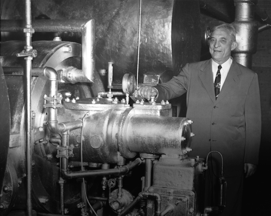Willis Carrier im Jahr 1950, hier mit der ersten je gebauten Turbokältemaschine, die 27 Jahre lang bei der Onondaga Pottery Company in Syracuse, New York, treue Dienste leistete. Die Carrier Corporation kaufte das Gerät zurück, um es der Smithsonian Institution in Washington, D.C., zur Verfügung zu stellen, wo es heute noch steht.