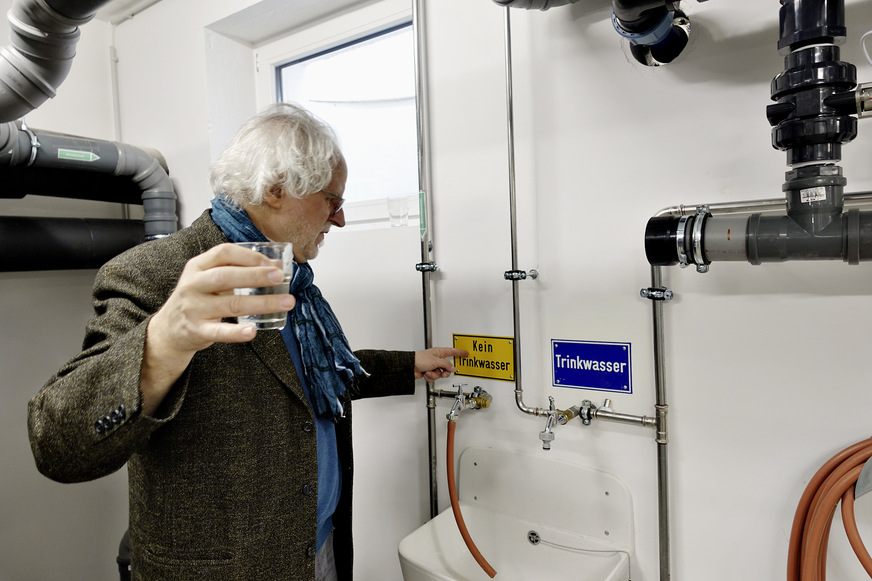 Bild 5 Probennahme im Technikraum durch den Planer Erwin Nolde. Das Betriebswasser aus dem aufbereiteten Grauwasser ist weder durch Geruch noch Optik vom Trinkwasser zu unterscheiden. Es passiert zum Abschluss der Reinigung einen Sandfilter und die UV-Desinfektion. Verwendung hier: Toilettenspülung.