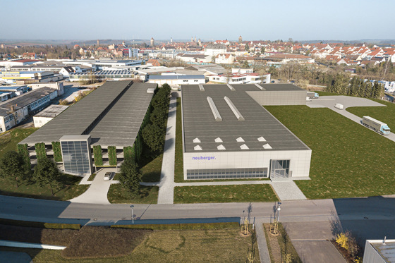 Die Visualisierung zeigt die beiden neuen Gebäude: links das Parkhaus, rechts daneben die Elektronikfertigung. Im hinteren Bereich der Logistikbereich mit separater Zufahrt.