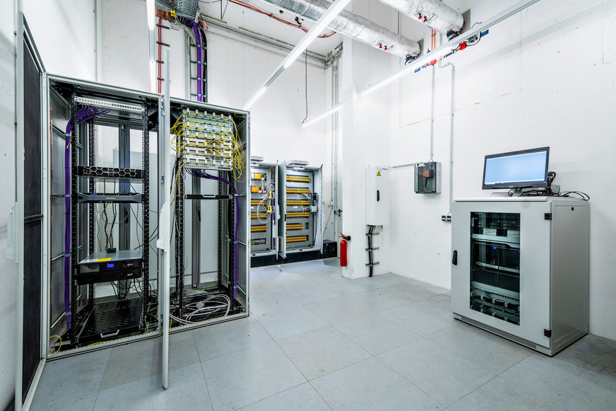 Bild 2 Serverschrank mit der Hardware und Software für das Hochleistungs-BMS im Humboldt Forum. Rechts hinten im Bild: Übergabeschränke und Brandmeldezentrale zur Entrauchungssteuerung: Alle Brandmeldeauslösungen mit den entsprechenden Brandbereichen im Gebäude werden hier von der Brandmeldeanlage an die Entrauchungssteuerung der Gebäudeautomation übergeben.