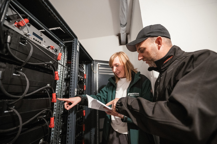 Bild 3 In der gebäudeeigenen Energiezentrale in der Bielefelder Holbeinstraße begutachten Melanie Kühl (naturstrom) und Gordon Grundorf (S|2 Gebäudetechnik) die Batteriespeicher.