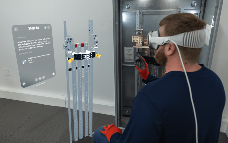 Mann, der einen Apple Vision Pro trägt, steht neben einem Siemens P5-Energieverteiler und betrachtet das digitale Overlay einer immersiven BILT-Anleitung mit 3D-Darstellung des Verteilers und einem Textfenster.