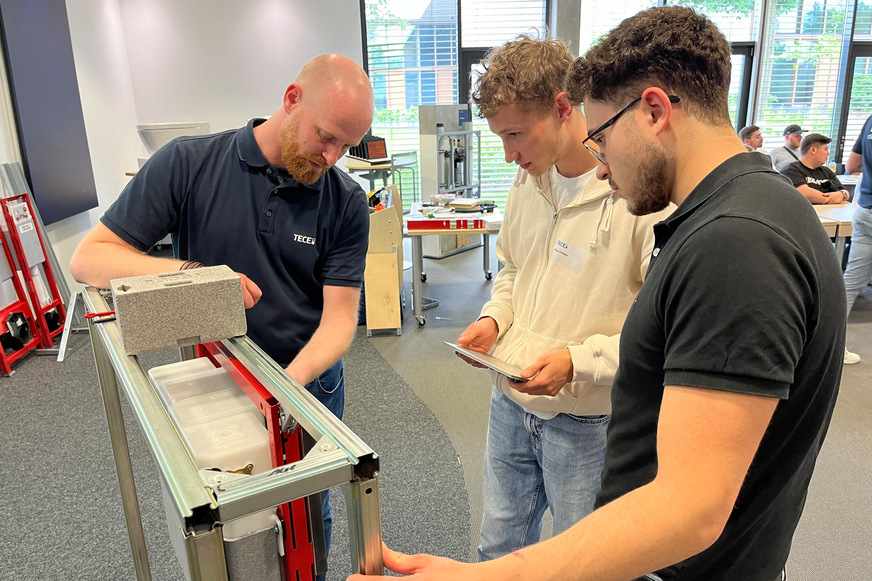 Philipp Hagedorn, Tece-Außendienst, unterstützt die Auszubildenden bei der Installation einer Solid-WC-Betätigungsplatte.