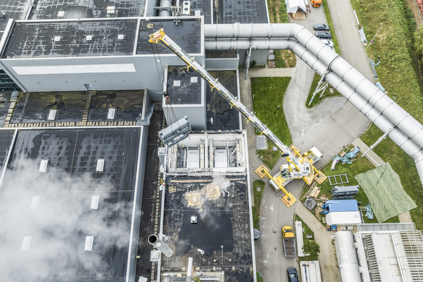 Bild 1 Mit einem Schwerlastkran wird eine Absorptionswärmepumpe an ihren Einsatzort gebracht.