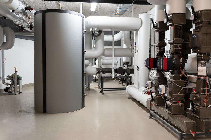 Drei der sechs Wärmepumpen sowie einer der beiden 2000-Liter-Pufferspeicher wurden vom restlichen Heizsystem entkoppelt und beheizen einen angrenzenden Altbau der EVM Berlin.