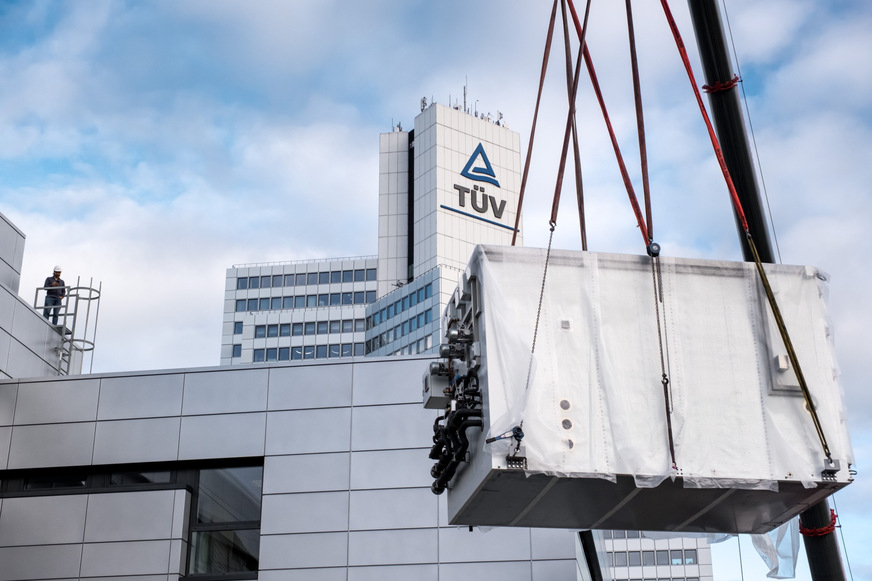 Eine der neuen Klimakammern für das Solarprüflabor wird zur Einbringöffnung mit einem Kran versetzt; …