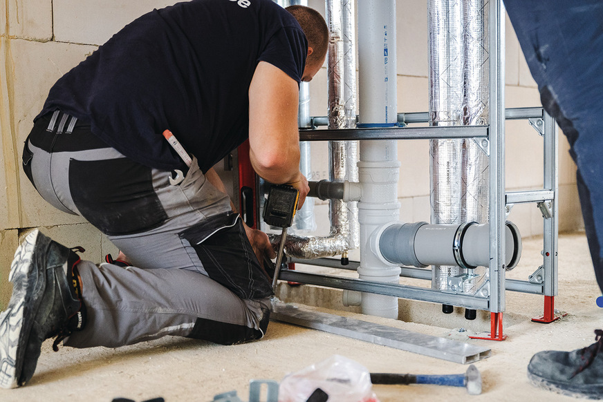 Ein Handwerker richtet die Installationswand am Boden aus.