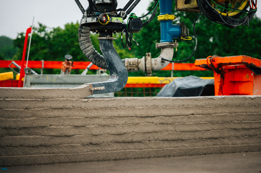 Ein automatisch gesteuerter Mastausleger des Betondruckers Instatiq P1 trägt Beton Schicht für Schicht auf.
