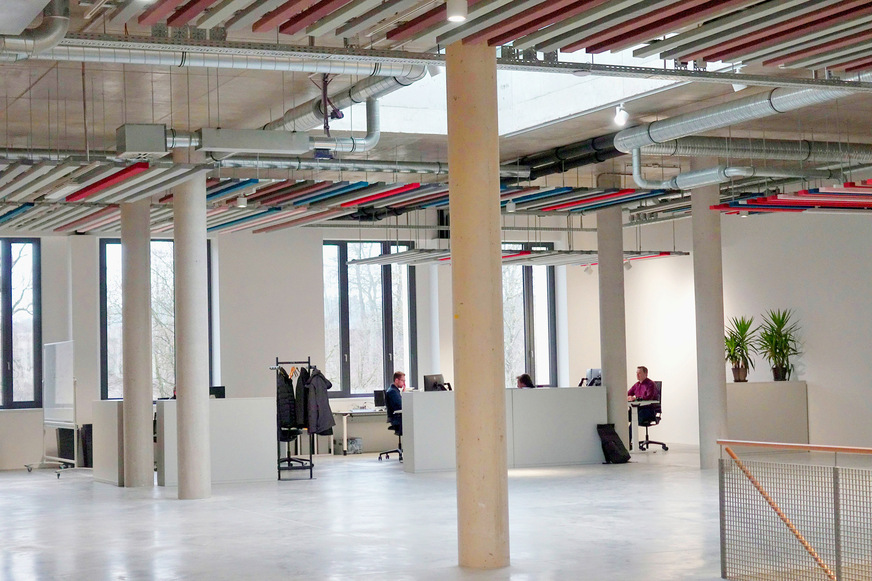 Bild 2 Büro im zweiten Obergeschoss mit einem offenen Grundriss in Anlehnung an die frühere industrielle Nutzung. Leitungen und Schallschutzlamellen sind Elemente der Raumgestaltung, der Boden ist als Sichtestrich ausgeführt.