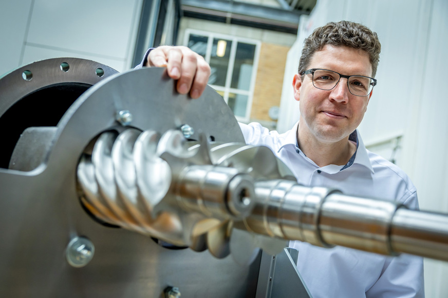 Prof. Simon Klink neben einem Verdichter für Industrieanwendungen.