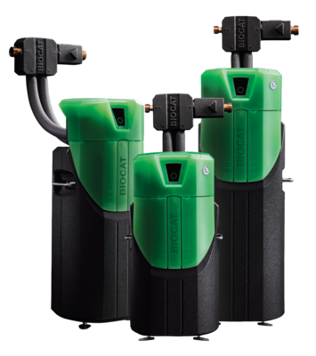 Drei grüne und schwarze BIOCAT-Wasseraufbereitungseinheiten mit Rohren und Anschlüssen auf weißem Hintergrund. - © Watercryst