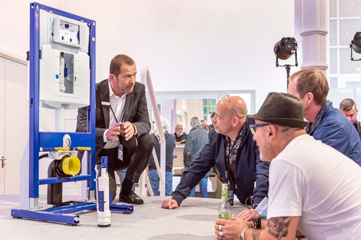 Interessierte Besucher unterhalten sich mit dem Geberit-Experten über den Unterputz-Spülkasten der Zukunft, inklusive neuem Spülventil Typ 212 sowie der neuen Elektro- und Kommunikations-anschlussdose.