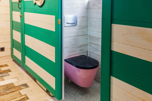 Die WC-Kabinen sind wie alte Strandumkleiden gestaltet, die pinkfarbenen Kartell Laufen WCs setzen dazu einen vergnüglichen optischen Kontrapunkt. - © Laufen
