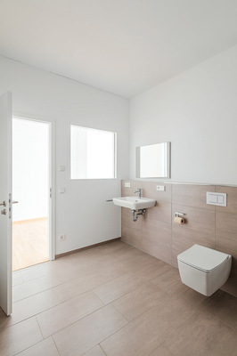 Hochwertige Ausstattung und großformatige Fliesen prägen das Erscheinungsbild des Badezimmers. Die Betätigungsplatte Tecenow knüpft an die geometrischen Formen des Gebäudes an.