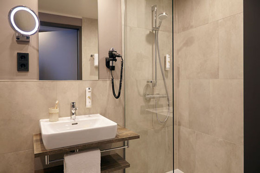 Die elegante Optik setzt sich in den Badezimmern fort, wo klare Formen auf zurückhaltende Farben treffen. - © Novum Hospitality
