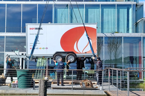 Die mobile Heizzentrale wird mit dem Kran auf der Terrasse platziert.