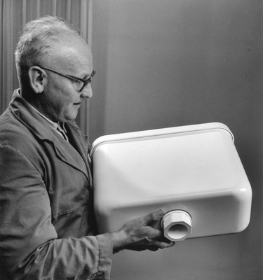  Ein Technischer Berater präsentiert einen der frühen Spülkastenmodelle aus PVC. Die Spülkästen komplett aus Kunststoff waren eine Weltneuheit in den 1950er-Jahren.