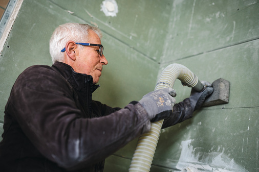 Einbringung der Einblasdämmung: Frank Hoffmann von der zertifizierten Firma Dachfit bringt in das fertig beplankte Modul das mineralische Dämmgranulat mit einem Schmelzpunkt von mehr als 1000 °C und einer Rohdichte von ca. 90 kg/m3  ein.