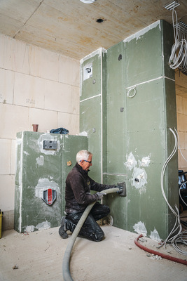 Ist das Modul vollständig beplankt, kann Frank Hoffmann in mehreren Schritten durch die vorbereiteten Öffnungen das Dämmgranulat einbringen.