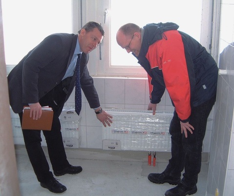 Fachplaner Lembke (rechts) und Kermi-Produktberater Carsten Hänsel prüfen es nach: Obwohl während der Umbauphase noch eingepackt und unter minimaler Teillast laufend, geben die Therm X-Flachheizkörper schon jetzt ihre Wärme gleichmäßig auf der gesamten Ansichtsfläche ab.