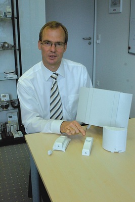 Arne Kähler, Bereichsleiter Geräteentwicklung bei Techem ­erläutert die Komponenten des ecotech-Systems: Batterie­betriebener Fernfühler-Funkheizkostenverteiler zur zentralen Erfassung der Vorlauftemperatur (links). Daneben der heute von Techem überwiegend installierte Funkheizkostenverteiler data III. Das ecotech-Modul (vorne) ist die Schnittstelle zur Heizung, der ecotech-MasterDatensammler (hinten) ermittelt die Vorlauftemperaturkorrektur.