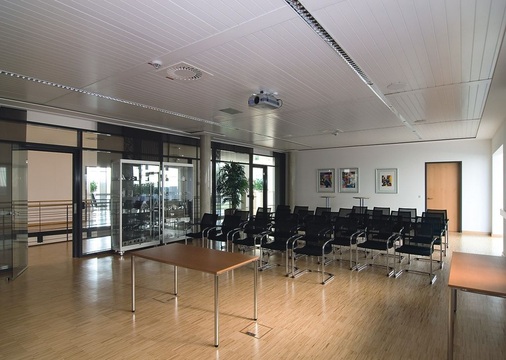 Lüftungsauslässe und Beleuchtungselemente wurden in die Zehnder Como Deckensegel integriert. Die Abluft wird durch eine Schattenfuge zwischen Deckensegel und Randfries abgeführt. Zudem konnten in Wallerstein allein durch die Installation der Kühl- und Heizelemente mit ihren akustischen Dämmfähigkeiten die Anforderungen an die Schallemissionsminderung erfüllt werden.