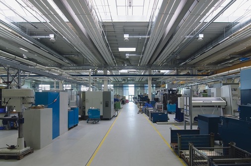 Die Praxis hat gezeigt, dass die hochgesteckten energetischen Ziele voll umgesetzt werden konnten: Die Fertigungshallen lassen sich mit den Deckenstrahlplatten wirtschaftlich temperieren. Detailmotiv: Hydraulischer Anschluss und Auflageschiene der Zehnder ZIP Deckenstrahlplatten.