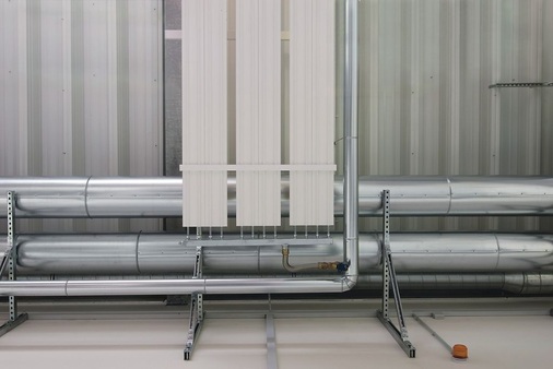 Die Praxis hat gezeigt, dass die hochgesteckten energetischen Ziele voll umgesetzt werden konnten: Die Fertigungshallen lassen sich mit den Deckenstrahlplatten wirtschaftlich temperieren. Detailmotiv: Hydraulischer Anschluss und Auflageschiene der Zehnder ZIP Deckenstrahlplatten.