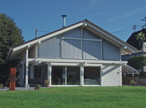Großzügige Fensterfronten und ein davor aufgestellter Kaminofen schließen sich nicht aus. So wird die schlichte Feuerstätte mit Specksteinummantelung zum doppelten Blickfang.