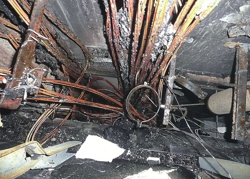 Gefahrenquelle in vielen Bestandsgebäuden: Unzureichende Brandabschottungen in Installationsschächten lassen diese im Brandfall zu wahren “Feuer- und Rauchverteilern“ werden. In wenigen Minuten breiten sich gefährliche Rauchgase auf anliegende Wohnungen und Geschosse aus. Das Foto zeigt nur noch die nackten Kupferleiter der Kabel. Die Kabelummantelungen sind vollständig verbrannt, von den brennbaren Rohrleitungen sind nur die Befestigungsschellen übrig geblieben.