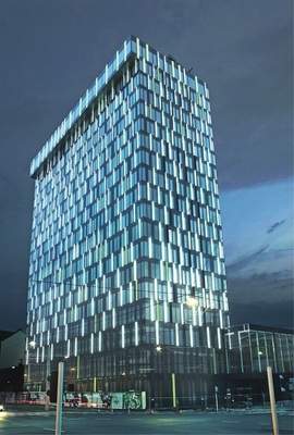 Power Tower in Linz. Nachts wird das Hochhaus durch rund 700 in der Fassade installierte LED-Lichtbänder illuminiert. Die Leistungsaufnahme des Lichtkunstwerks wird mit maximal 1,4 kW angegeben. An der Südwestseite des Towers ­liefert eine 650-m2-Photovoltaikanlage mit 66 kWp rund 42000 kWh/a.