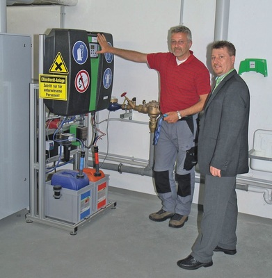 Abb. 5 Die automatisch arbeitende Chlordioxiderzeugungs­anlage sorgt für die Einhaltung der Trinkwasserhygiene. Grünbeck-Vertriebs­leiter Jürgen Weißenburger (rechts) kontrolliert den ordnungsgemäßen Anschluss der beiden Chemikalienbehälter, aus deren Inhalt das Chlordioxid ­gemischt wird.