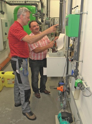 Abb. 4 Stephan Herreiner (rechts) von Grünbeck ­erläutert dem Betriebstechniker die Kontrolle der Wasserparameter an der Mess- und Regel­anlage für die Schwimmbadwasseraufbereitung. - © Grünbeck
