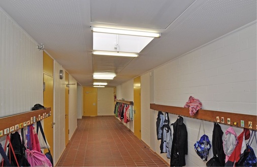 Abb. 5 Die Flure haben nach dem Rückbau des Dachs und der ­Sanierung der Lichtkuppeln wieder ­Tageslicht. Die Heiz-/ Kühlelemente wurden passgenau eingesetzt.