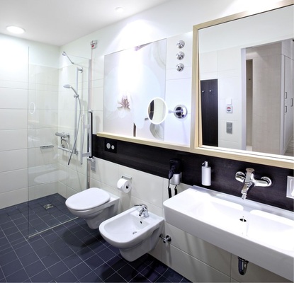Abb. 4 Die zu jedem Zimmer gehörenden Bäder sind mit einem großzügigen, eleganten Waschtisch, einem wandhängenden Bidet und WC sowie einer transparenten Dusche ausgestattet. Die Sanitärkeramik ist mit der Spezialglasur KeraTect ausgerüstet, die durch ihre nahezu porenfreie, extrem glatte Oberfläche das Anhaften von Schmutz und Bakterien weitgehend verhindert und somit höchste Hygiene im Bad sicherstellt.