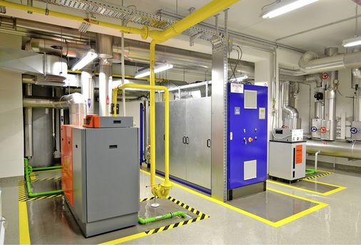 Abb. 2 Wärmeerzeuger-Kombination: Gas-Brennwertheizkessel von Remeha (links) und ein gasmotorisches BHKW von Oeko Sommer. Vor dem Betonpfeiler steht eine Entgasungsstation für das Heizungswasser.