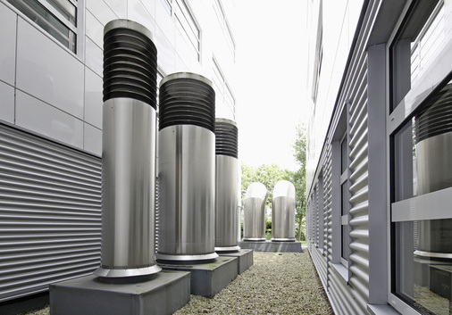 Abb. 2 …sind die Zu- und Ablufttürme im Lichthof auf der Gebäuderückseite der einzige sichtbare Hinweis auf ein klimatisiertes Gebäude. Durch die Einkopplung der Kondensatorwärme aus den Kältemaschinen in das GSWT-System konnte auf ein Rückkühlbauwerk mit einer Leistung von etwa 1300 kW bzw. einer Luftmenge von ca. 220000 m³/h verzichtet werden.