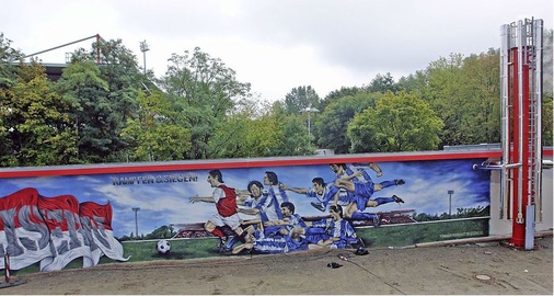 Abb. 3 Fast vollendet: Das Wandgemälde auf der Längsseite der Heizzentrale zeigt das „Unioner“-Gefühl, farblich passend wie die Abgasanlage rechts.
