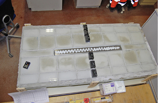 <p>Bild 7  Der Prüfkörper mit Duschrinne nach 15 Tagen Trocknung. Immer noch sind durchfeuchtete Bereiche unter den Fliesen mit bloßem Auge deutlich erkennbar. Diese finden sich vor allem in der Mitte der Fliesen, wo die Wege für die Diffusion zur Umgebungsluft länger sind.</p> - © OFI Bild 7  Der Prüfkörper mit Duschrinne nach 15 Tagen Trocknung. Immer noch sind durchfeuchtete Bereiche unter den Fliesen mit bloßem Auge deutlich erkennbar. Diese finden sich vor allem in der Mitte der Fliesen, wo die Wege für die Diffusion zur Umgebungsluft länger sind.