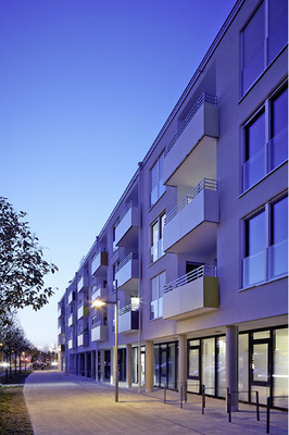 



4
 Zur Straße hin bildet die Wohnanlage eine strenge, geometrische Geschlossenheit. Im Erdgeschoss befinden sich ein Bäcker und Arztpraxen – das Wohnumfeld ist für Mieter wichtig, dazu gehören ärztliche Angebote im Quartier. 
