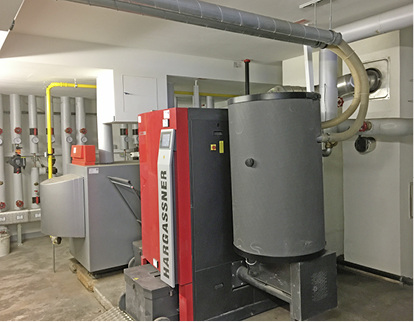 



4
 Heizraum im Untergeschoss des Hauses Grabenäckerstraße 15. Der Grundlast-Heizkessel für Holzpellets, mit dem außen liegenden unterirdischen Pelletspeicher durch flexible Schläuche/Saugsystem verbunden, daneben Spitzenlast-Heizkessel (Gas). Im April 2016 wurden die Wärmeerzeuger ausgetauscht und das Nahwärmenetz komplett erneuert – bei voller Belegung der 64 Wohnungen. 
