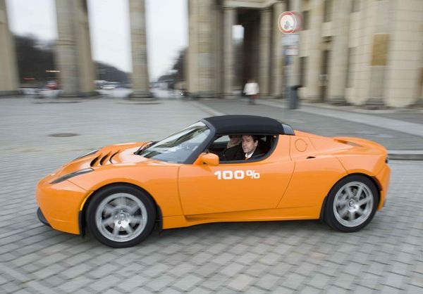 Juwi-Gründer und -Vorstand Matthias Willenbacher fährt mit seinem Elektro-Roadster Tesla vor dem Brandenburger Tor vor. Der 100-%-Sticker am Tesla steht für die Zukunftskampagne von juwi, mit der das Unternehmen die Umstellung auf eine Stromversorgung forciert, die komplett aus erneuerbaren Energien gespeist wird. - juwi/Landrock