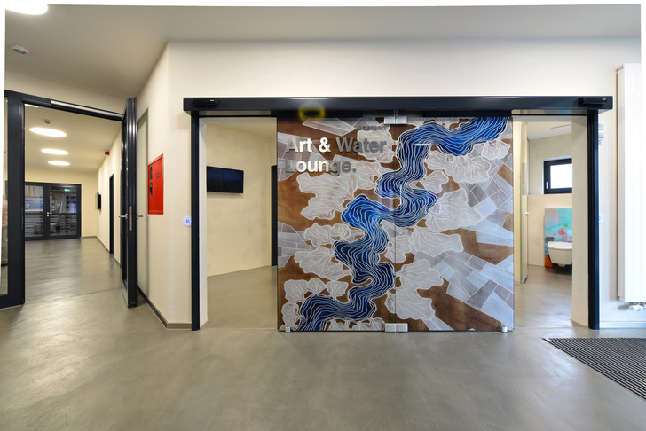 Aus den Sanitärräumen entstand bei der Modernisierung die “Geberit Art & Water Lounge“. Das Eingangsbild der Sanitärräume stilisiert die regionale Muldenlandschaft. - © Geberit
 Aus den Sanitärräumen entstand bei der Modernisierung die “Geberit Art & Water Lounge“. Das Eingangsbild der Sanitärräume stilisiert die regionale Muldenlandschaft. - Geberit